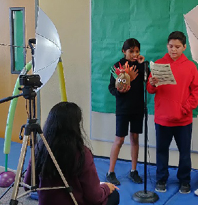 Two students presenting in front of a video camera